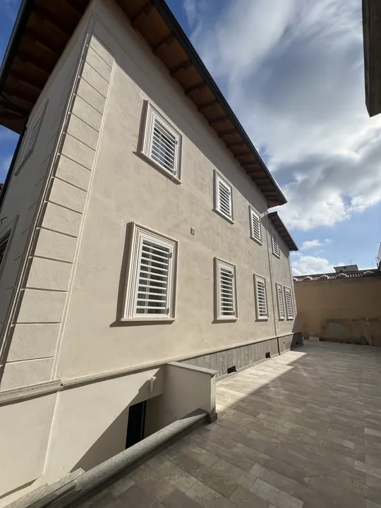Facciata di una casa a due piani con persiane blindate bianche a tutte le finestre