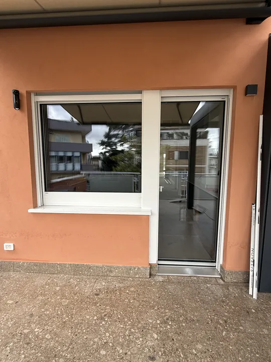 Finestra e portafinestra nuove con telaio bianco sotto una pergola